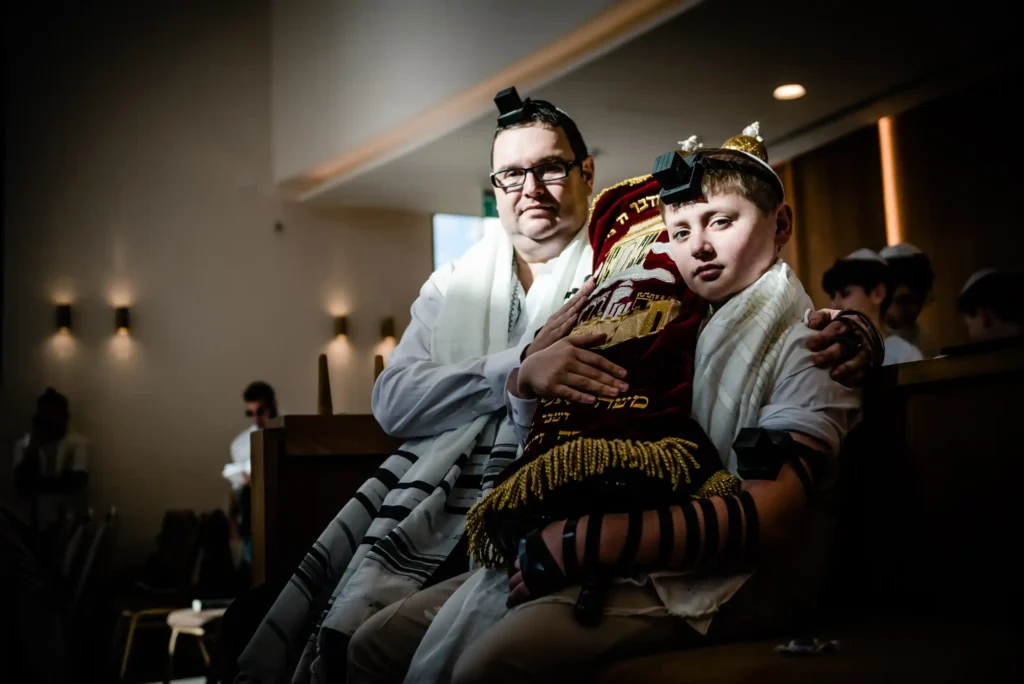 אבא ובן מחזיקים ספר תורה בבית הכנסת